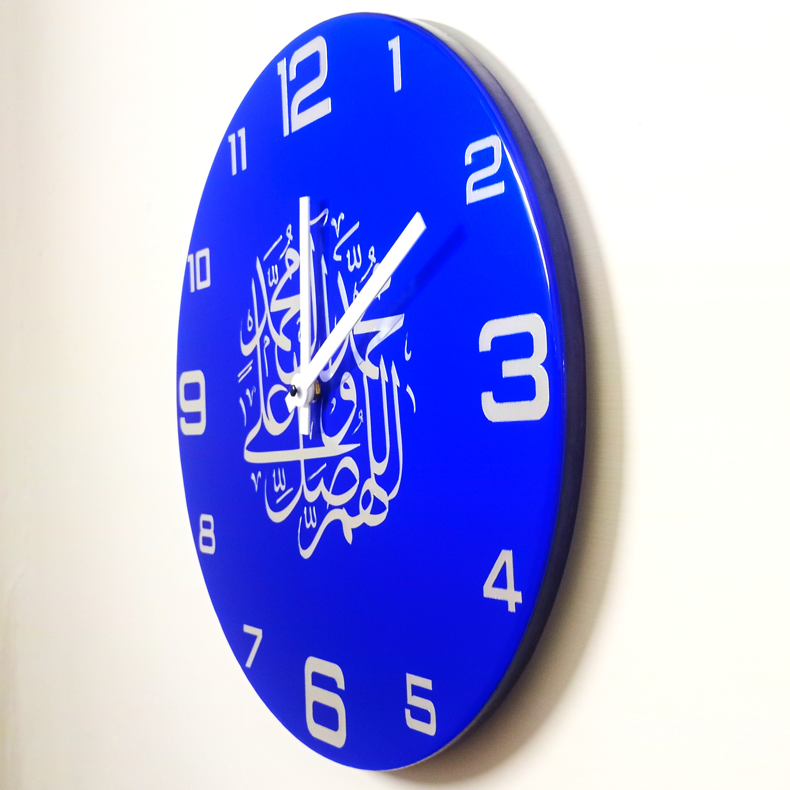 Royal blue resin clock with white numerals and intricate Arabic calligraphy design.